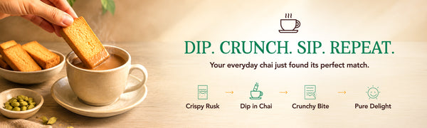 hand holds a biscuit above a cup of chai on a saucer with Anil rusk